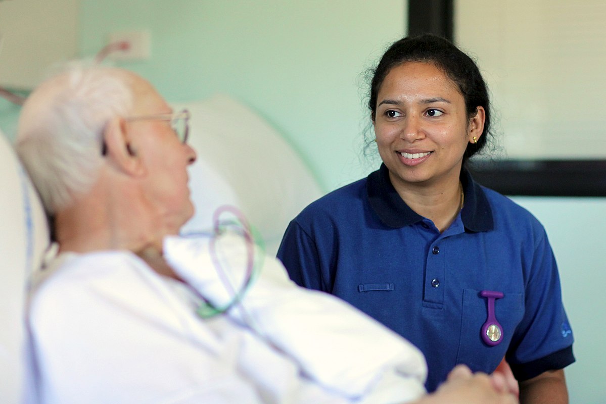Senior patient in hospital bed with nurse